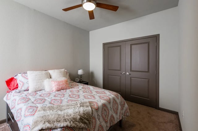 Bed with patterned duvet plush pillows large closet bedroom at The Quarters at Stillwater in Stillwater Student Accommodation
