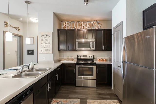 Stainless steel fridge dark cabinets oven sink kitchen at The Quarters at Stillwater in Stillwater Student Accommodation