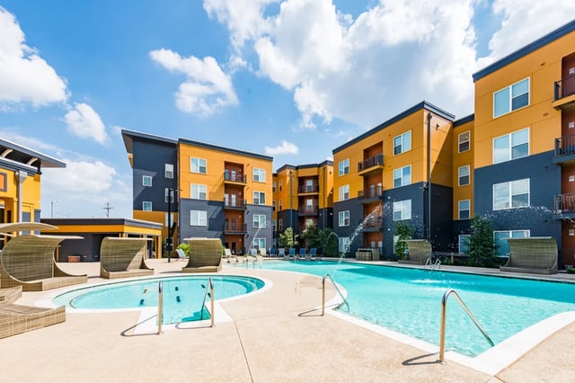 Pool area with lounge chairs and apartment buildings exterior at The Quarters at Stillwater in Stillwater Student Accommodation