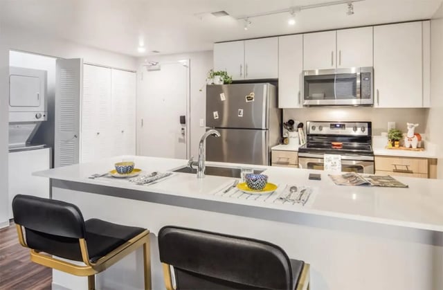 Bar stools at island sink stove refrigerator kitchen at Rise At Riverfront Crossings in Iowa City Student Accommodation