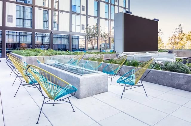 Chairs fire pit and large screen exterior at Rise At Riverfront Crossings in Iowa City Student Accommodation