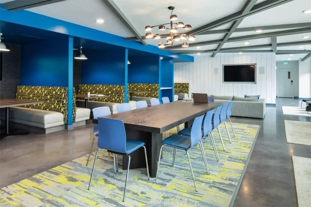 Large table blue chairs booths modern lounge area at Rise At Riverfront Crossings in Iowa City Student Accommodation
