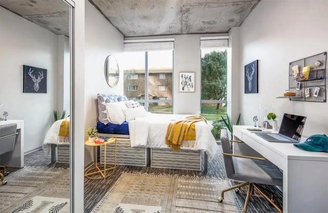 Bed desk mirror rug and artwork bedroom at Rise At Riverfront Crossings in Iowa City Student Accommodation