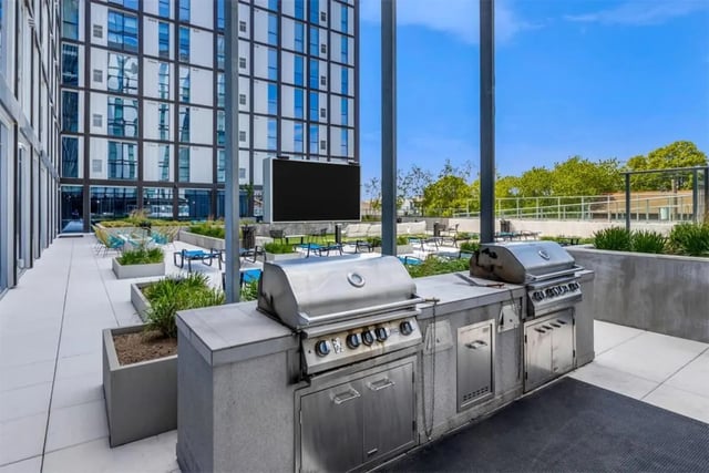 Outdoor grills with seating area and building exterior. at Rise At Riverfront Crossings in Iowa City Student Accommodation