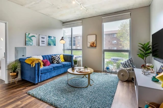 Blue sofa large rug coffee table living room at Rise At Riverfront Crossings in Iowa City Student Accommodation