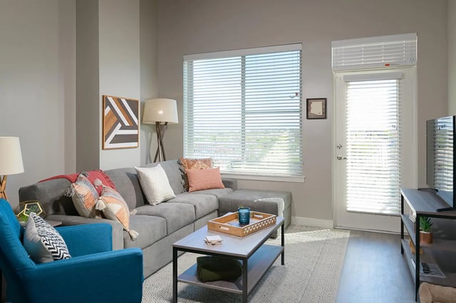 Gray sectional sofa coffee table and blue chair living room at The Mark at Tucson in Tucson Student Accommodation