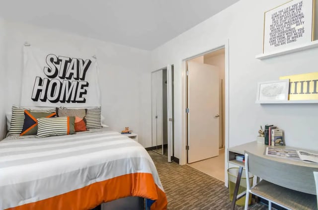 Bed with pillows rug desk and inspirational wall art bedroom at Rise On 9th in Columbia Student Accommodation