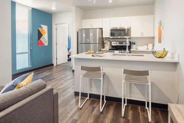 Modern kitchen island with stools and sofa living room at Rise On Chauncey in West Lafayette Student Accommodation