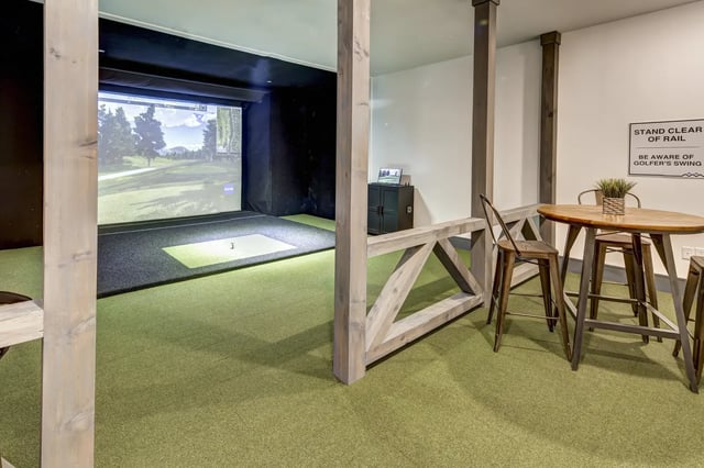 Golf simulator with putting area and bar seating playing area at The Retreat at Denton in Denton Student Accommodation