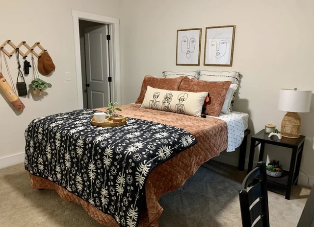 Bed with patterned throw artwork and nightstand bedroom at The Retreat at Denton in Denton Student Accommodation