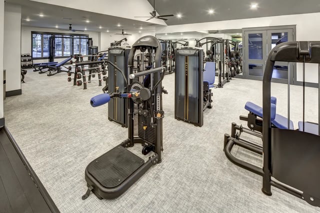 Gym equipment with weight stacks and benches fitness area at The Retreat at Denton in Denton Student Accommodation