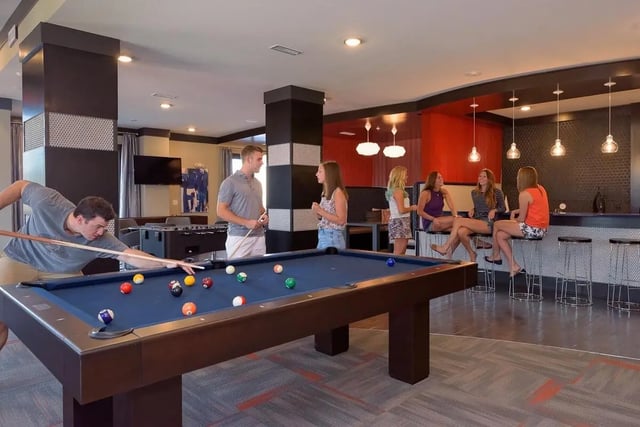 Pool table with people playing and sitting at bar playing area at The Standard in St. Louis Student Accommodation