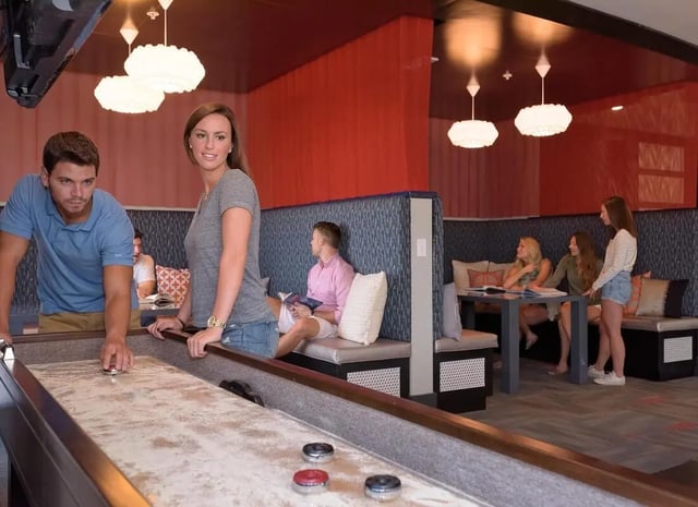 Shuffleboard game with people in lounge area Game room at The Standard in St. Louis Student Accommodation