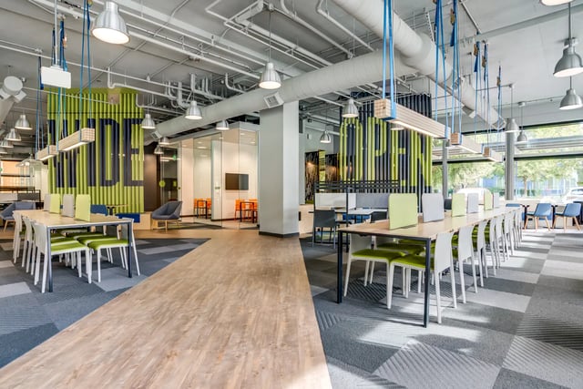 Study tables chairs and glass-walled meeting rooms communal area at SOL at West Village in Davis Student Accommodation