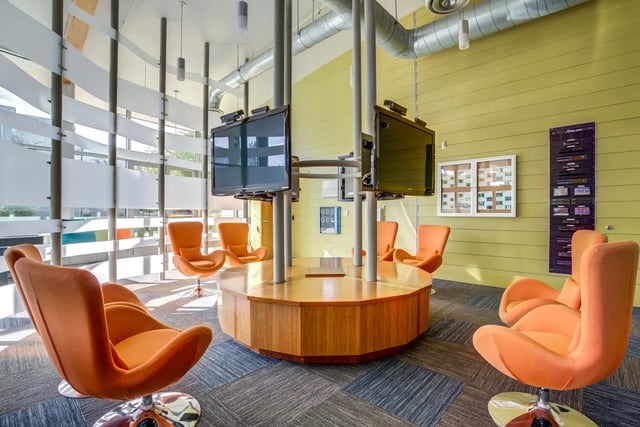 Orange chairs around central table with screens common area at SOL at West Village in Davis Student Accommodation