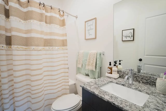 Striped shower curtain toilet sink vanity bathroom at The Retreat at Illinois in Urbana Student Accommodation
