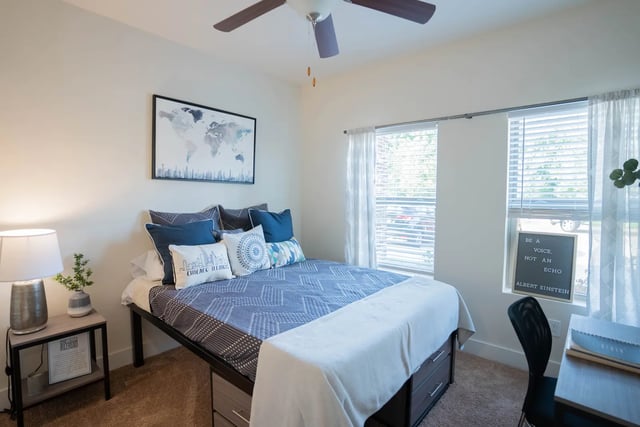 Bed with blue pillows and world map Bedroom at The Retreat at Illinois in Urbana Student Accommodation