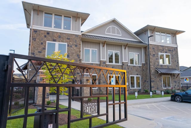 Stone building with gate and parking exterior at The Retreat at Illinois in Urbana Student Accommodation