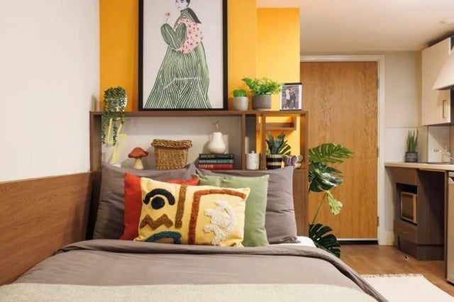 Bed with decorative pillows shelving unit kitchenette exterior at Sugarhouse in Edinburgh Student Accommodation