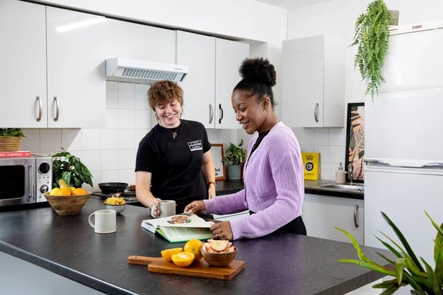 Two students in kitchen looking at cookbook kitchen at Clodien House in Cardiff Student Accommodation