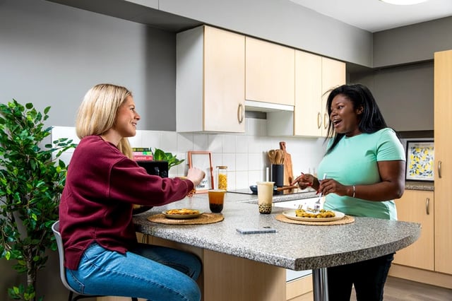 Two students eating at kitchen island kitchen at Raglan House in Coventry Student Accommodation