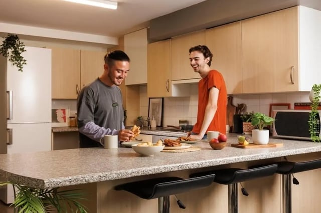 Two men eating food at a kitchen counter kitchen at The Tannery Leeds in Leeds Student Accommodation