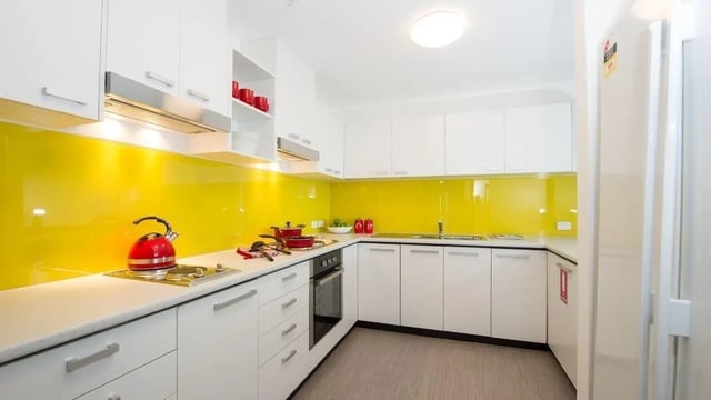White cabinets red kettle stove oven yellow backsplash kitchen at UniLodge Victoria University in Melbourne Student Accommodation