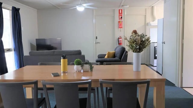 Dining table chairs sofa television living room at La Trobe University - Terraces in Melbourne Student Accommodation