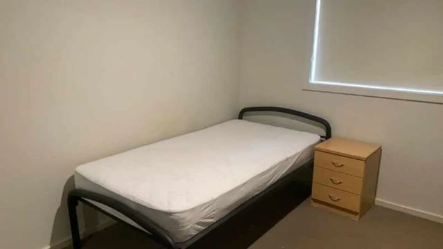 Bed with white mattress and bedside table bedroom at La Trobe University Regional Housing - Shepparton in Shepparton Student Accommodation