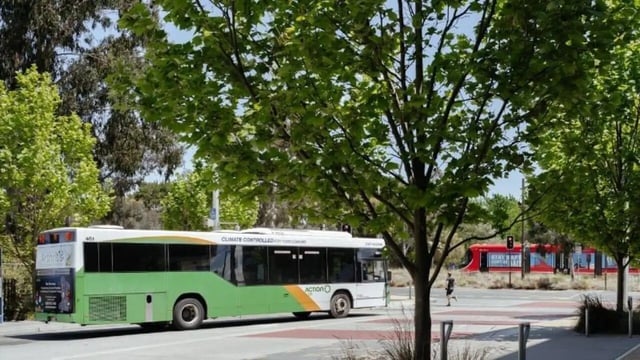 Green and white bus parked on street exterior at Dickson Village Apartments in Canberra Student Accommodation
