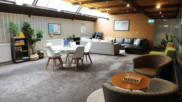 Modern lounge with sofas chairs tables and plants living room at La Trobe University - Chisholm College in Melbourne Student Accommodation