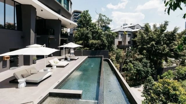 Daybeds umbrellas pool lounge area exterior at Realm Kangaroo Point in Brisbane Student Accommodation