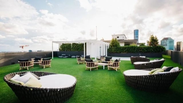 Wicker daybeds and chairs on grassy rooftop area at Realm Kangaroo Point in Brisbane Student Accommodation