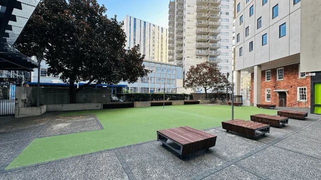 Wooden benches on green lawn courtyard exterior at Wellesley Apartments in Auckland Student Accommodation