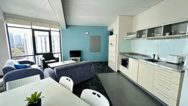 Sofas chairs table kitchen counter living room kitchen at Wellesley Apartments in Auckland Student Accommodation