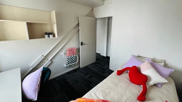 Bed with pillows shelves and a door Bedroom at Wellesley Apartments in Auckland Student Accommodation