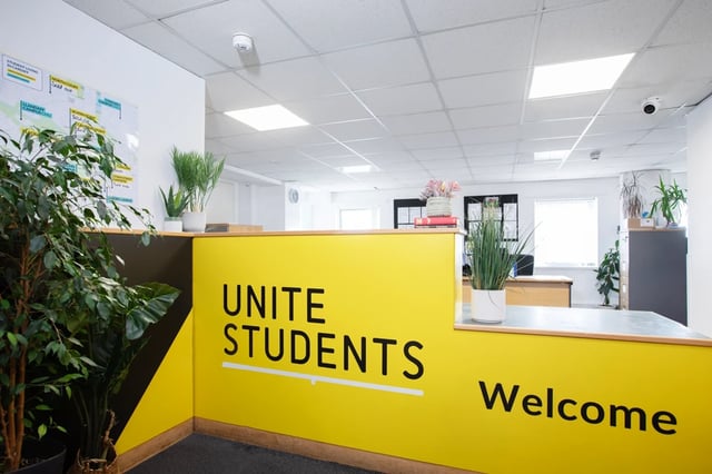 Yellow reception desk with plants and Unite Students welcome desk interior at Ty Pont Haearn in Cardiff Student Accommodation
