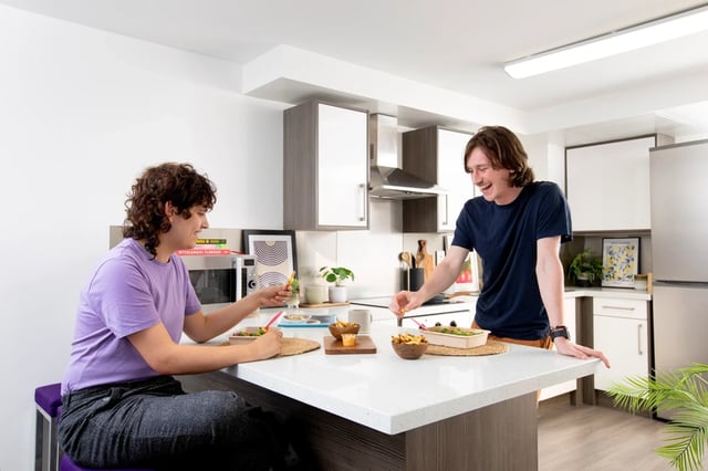 Two people eating at kitchen island kitchen at Ty Pont Haearn in Cardiff Student Accommodation
