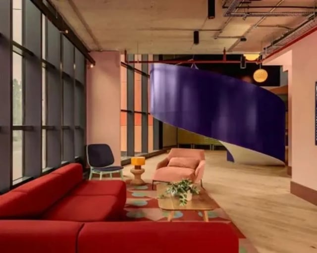 Red sofa coffee table chairs staircase living room at Scape Hammersmith in London Student Accommodation