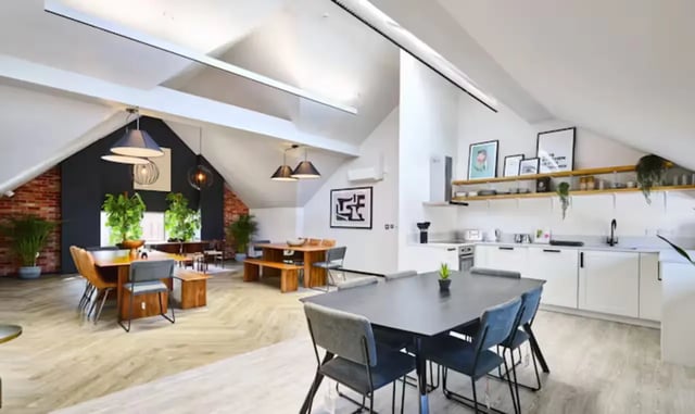 Dining tables chairs kitchen and plants common area at Frederick House in York Student Accommodation