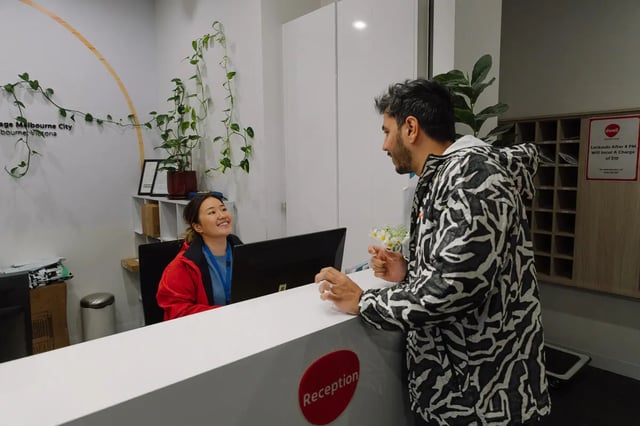 Reception desk with two people and plants reception at dwell Village Melbourne City in Melbourne Student Accommodation