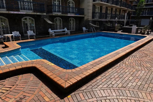 Blue tiled swimming pool with brick surround pool area at dwell Village Melbourne City in Melbourne Student Accommodation
