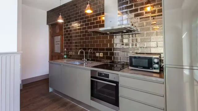 Modern grey cabinets oven microwave tiled backsplash kitchen at Gillows in Lancaster Student Accommodation