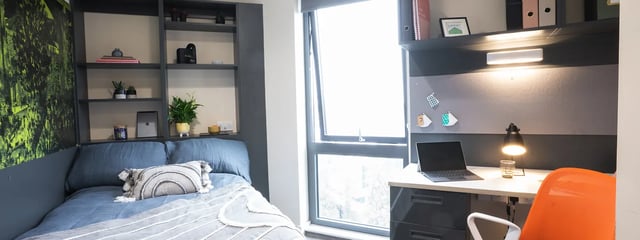 Bed desk shelving and bright orange chair bedroom at Oxford House - Newcastle in Newcastle Upon Tyne Student Accommodation