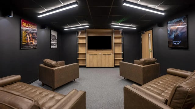 Brown leather couches facing TV and shelves living room at Medici in Nottingham Student Accommodation