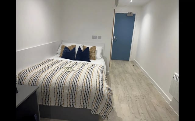 Bed with pillows and blanket door and heater bedroom at Medici in Nottingham Student Accommodation