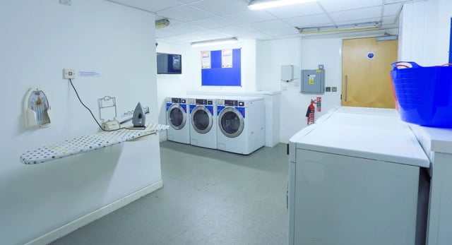 Ironing board washing machines fire extinguisher laundry room at Griffon Studios in London Student Accommodation