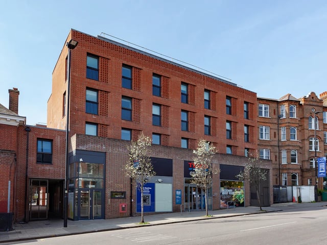 Modern red brick building with shops and windows exterior at Academic House in London Student Accommodation