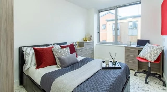 Bed with cushions desk with laptop and chair bedroom at Queens Gate in Southampton Student Accommodation