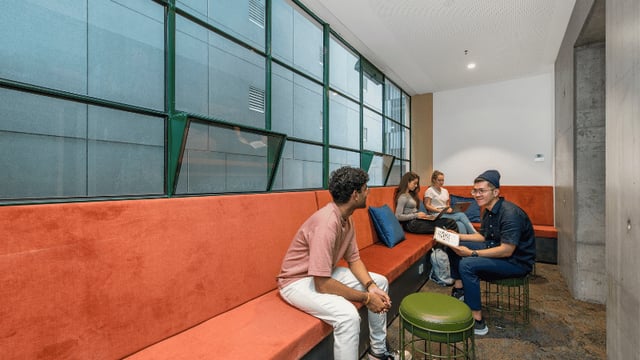 Students on orange bench with laptops communal area at UniLodge Melbourne Flagstaff in Melbourne Student Accommodation